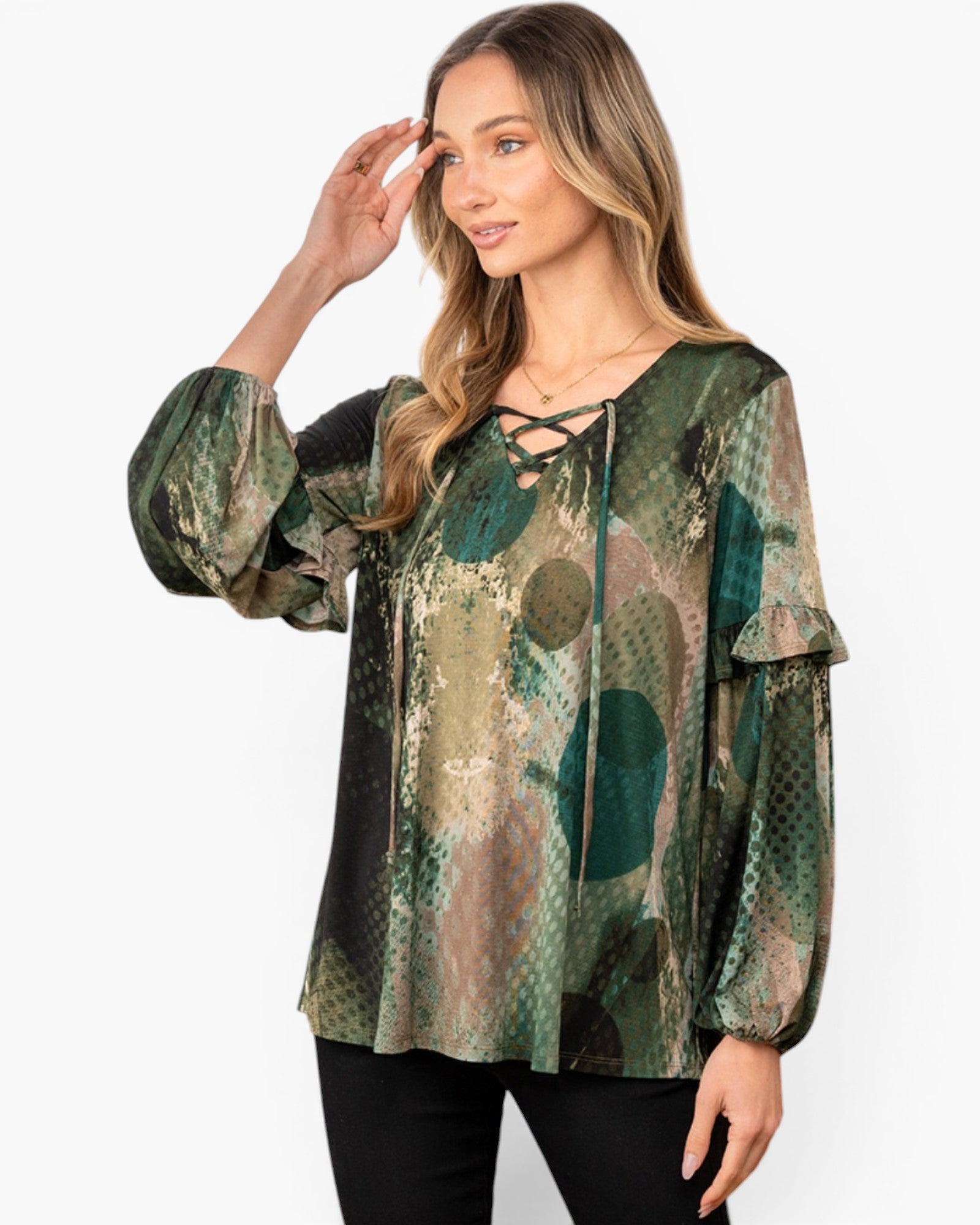 A woman modeling a long-sleeve blouse with a green, brown, and beige abstract pattern, featuring a lace-up neckline and ruffled sleeves, set against a plain white background.