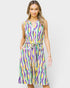 A woman modeling a sleeveless midi dress with a colorful wavy abstract pattern in purple, green, yellow, and white, featuring a tie waist belt and side pockets, set against a plain light gray background.