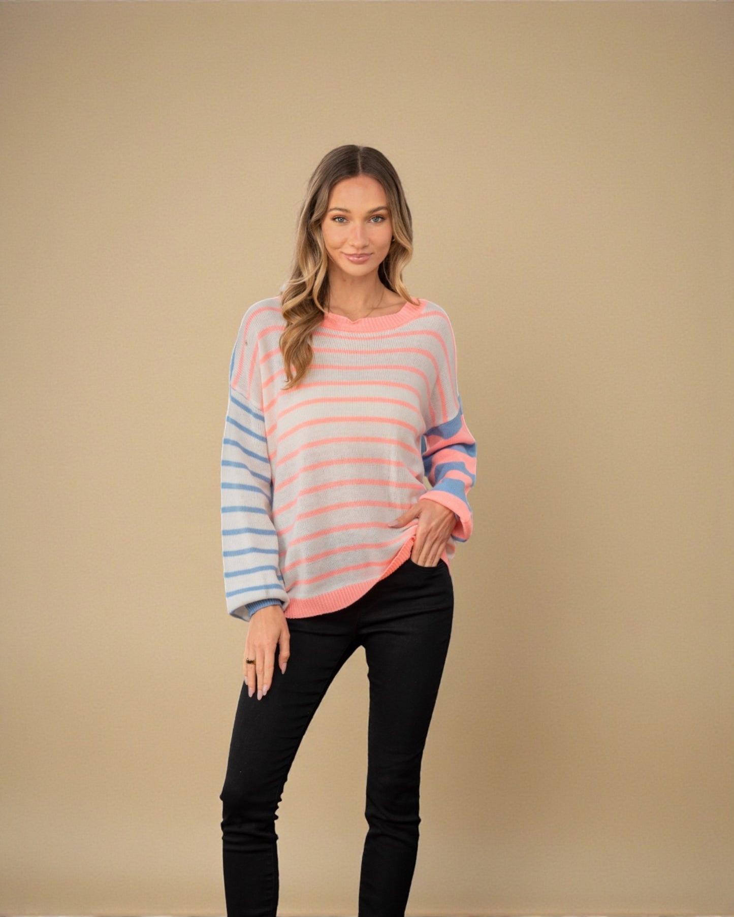 Woman wearing a striped sweater and black pants against a beige background