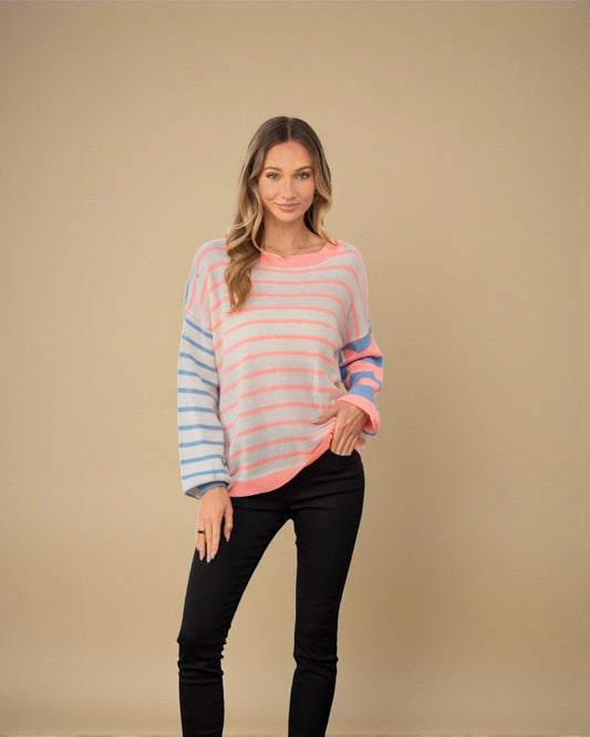 Woman wearing a striped sweater and black pants against a beige background