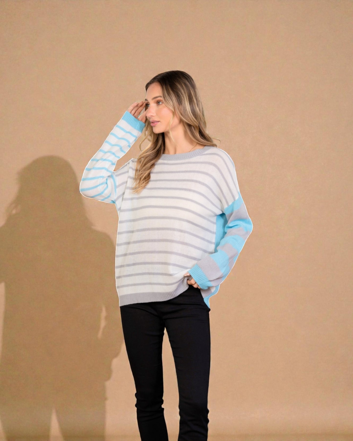 Woman wearing a striped sweater with blue sleeves against a beige background