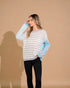 Woman wearing a striped sweater with blue sleeves against a beige background