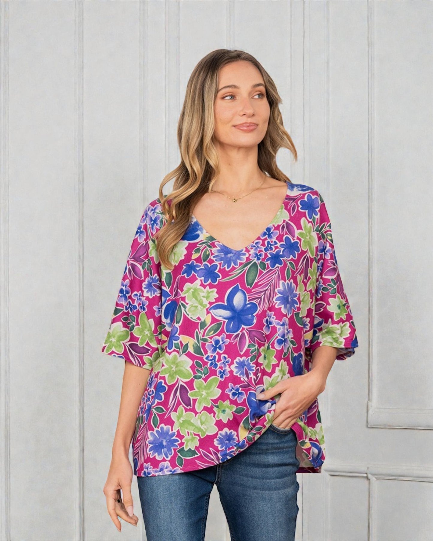 Woman wearing a colorful floral blouse against a white background