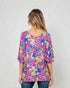 Woman wearing a colorful floral blouse against a white background