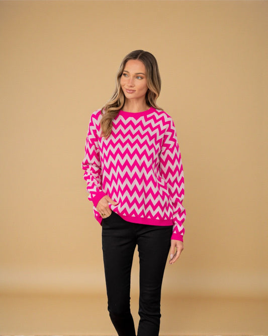 Woman wearing a pink and white zigzag pattern sweater against a beige background