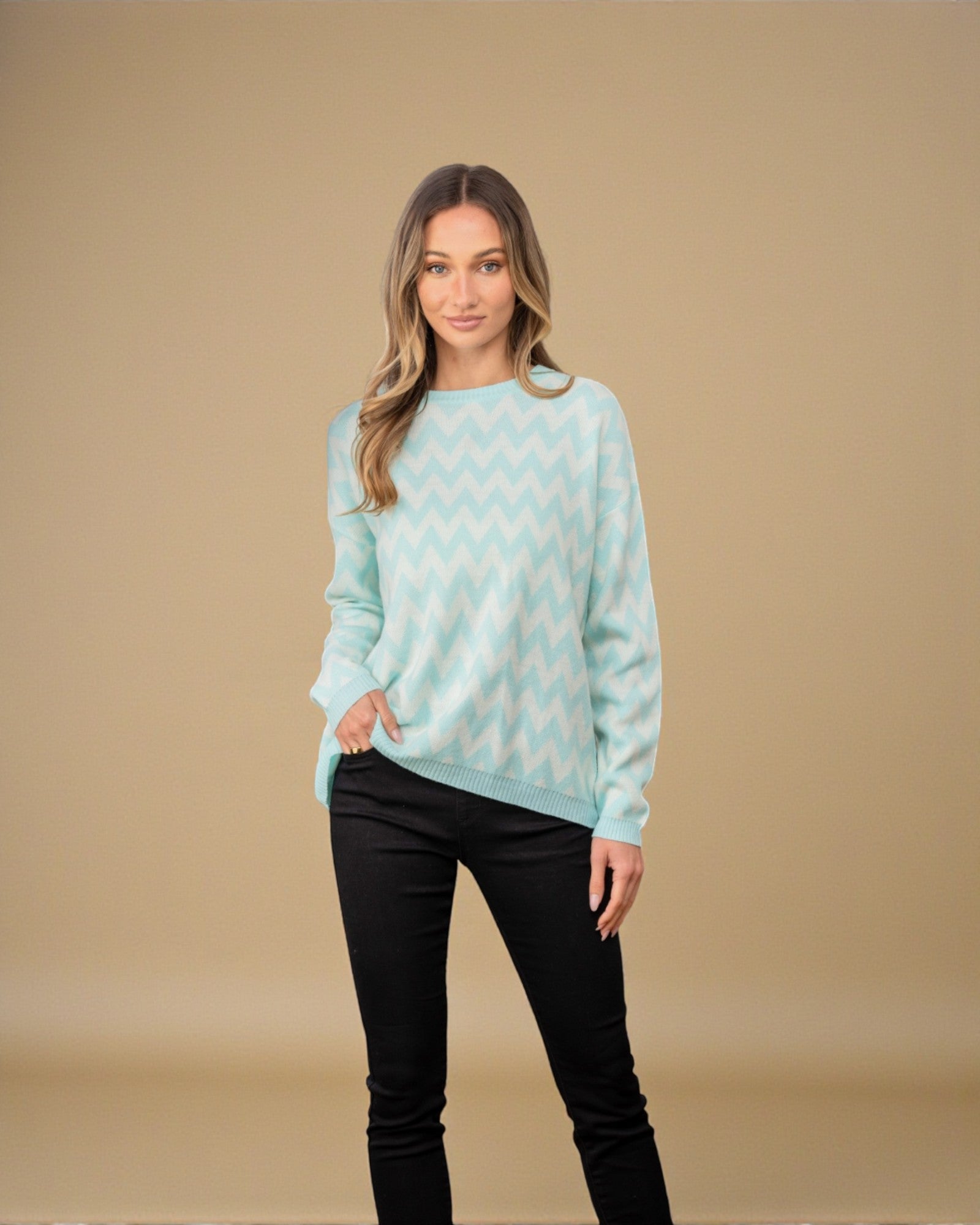 Woman wearing a light blue sweater with a pattern against a beige background