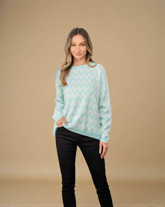 Woman wearing a light blue sweater with a pattern against a beige background