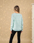 Person wearing a light blue sweater with a subtle pattern against a beige background