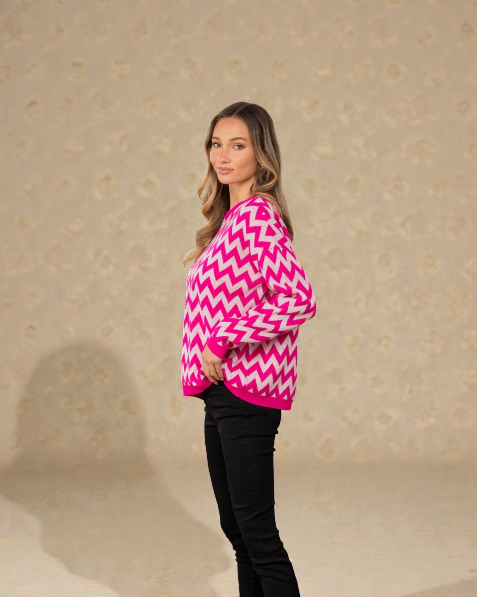Woman wearing a pink and white zigzag patterned sweater against a beige background