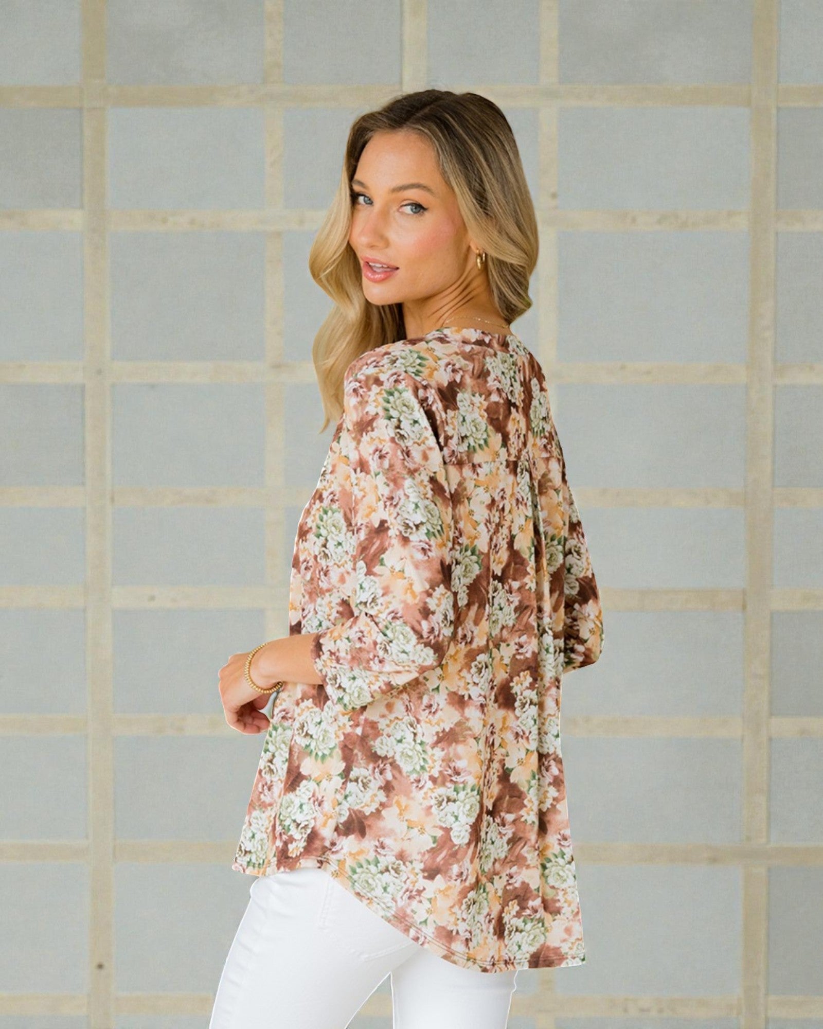 Woman wearing a floral blouse against a tiled wall background