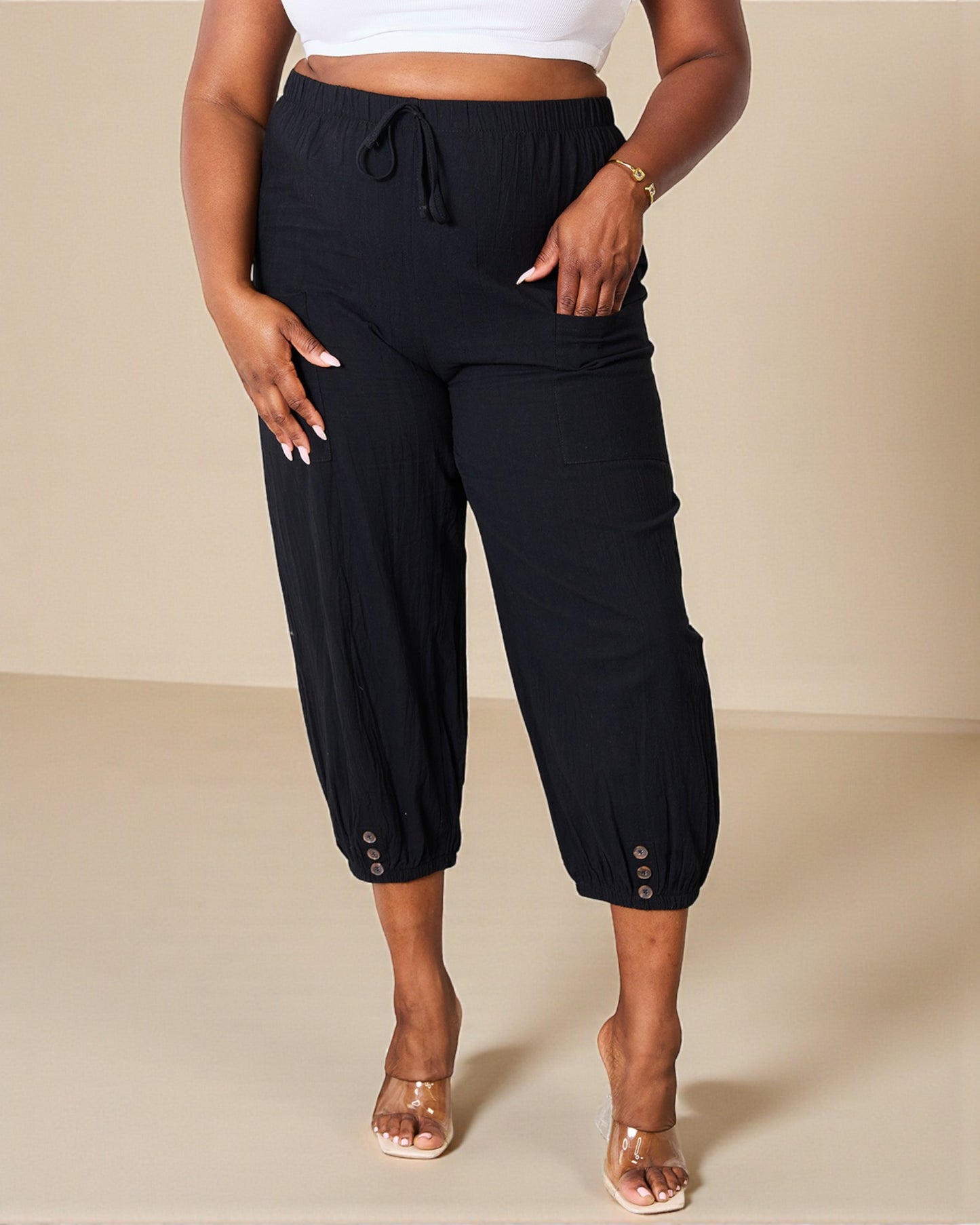 Person wearing black capri pants with a beige background