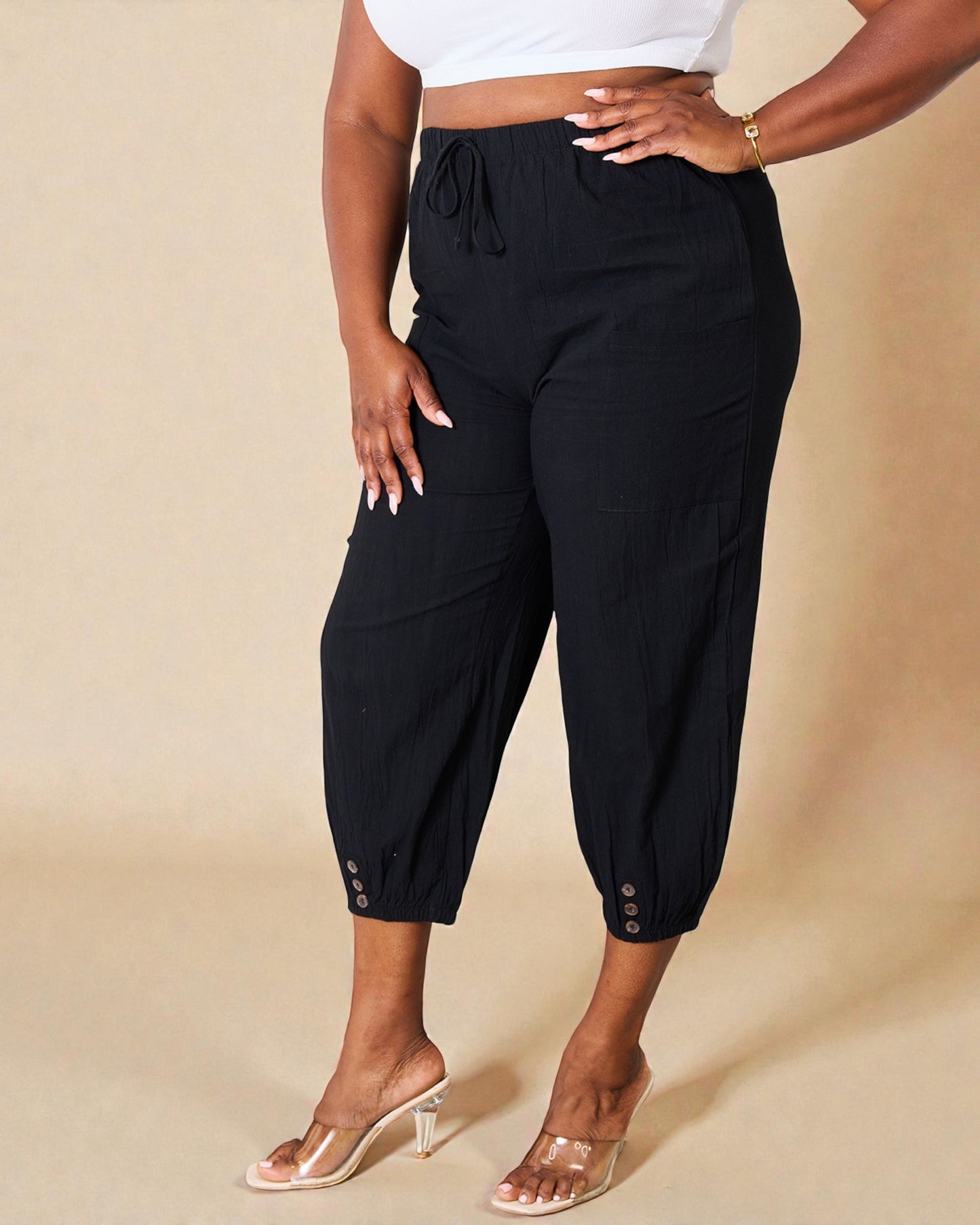 Person wearing black capri pants on a beige background