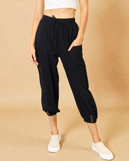 Person wearing black drawstring pants on a beige background