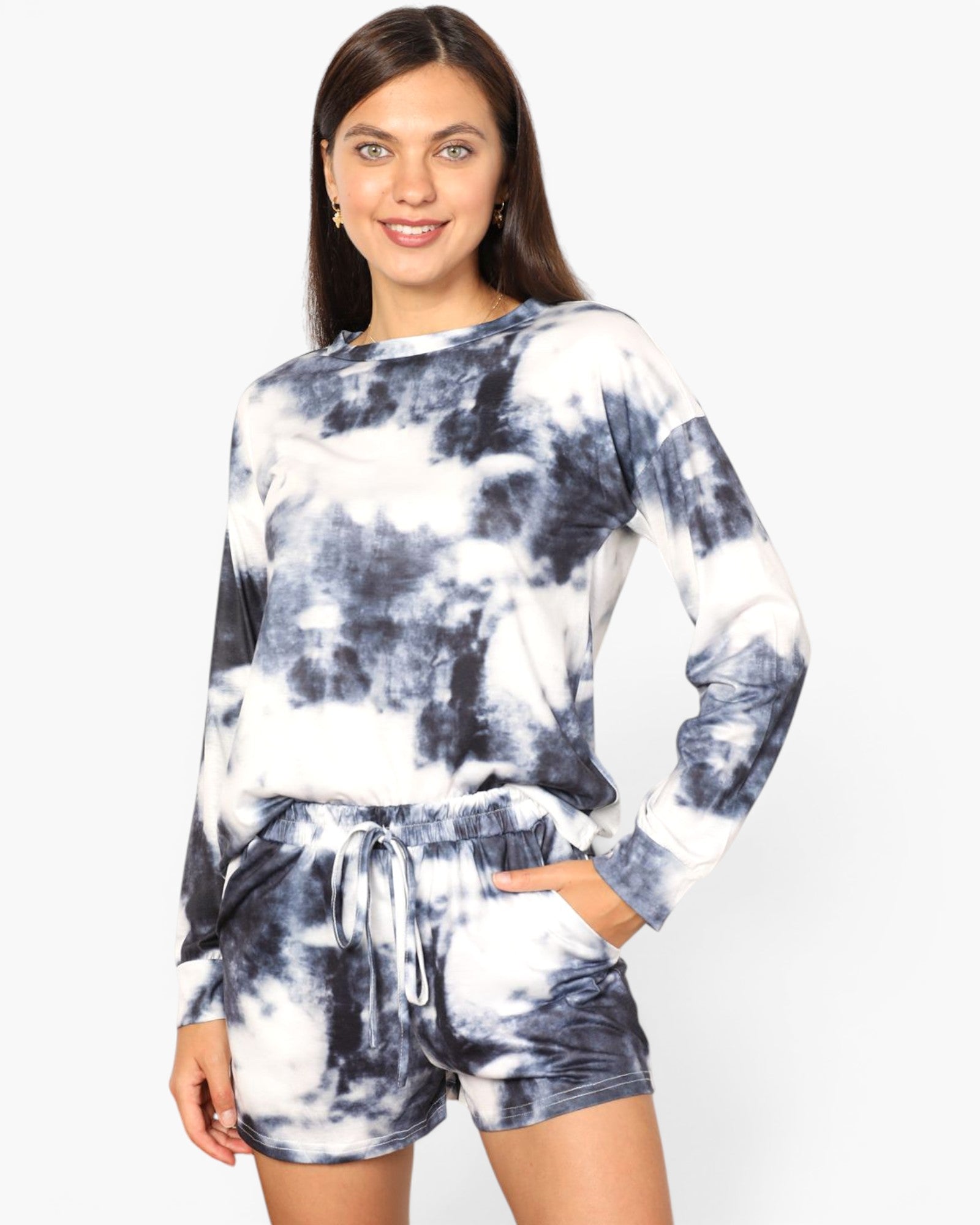 A woman modeling a matching long-sleeve top and shorts lounge set in a navy and white tie-dye pattern, set against a plain light gray background.