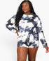 A woman modeling a matching long-sleeve top and shorts set in a black and white tie-dye pattern against a plain white background.