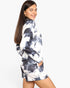 A woman modeling a matching tie-dye lounge set consisting of a long-sleeve top and shorts in a black and white swirl pattern, photographed against a solid white studio background.