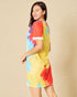 Woman wearing a colorful tie-dye dress on a beige background