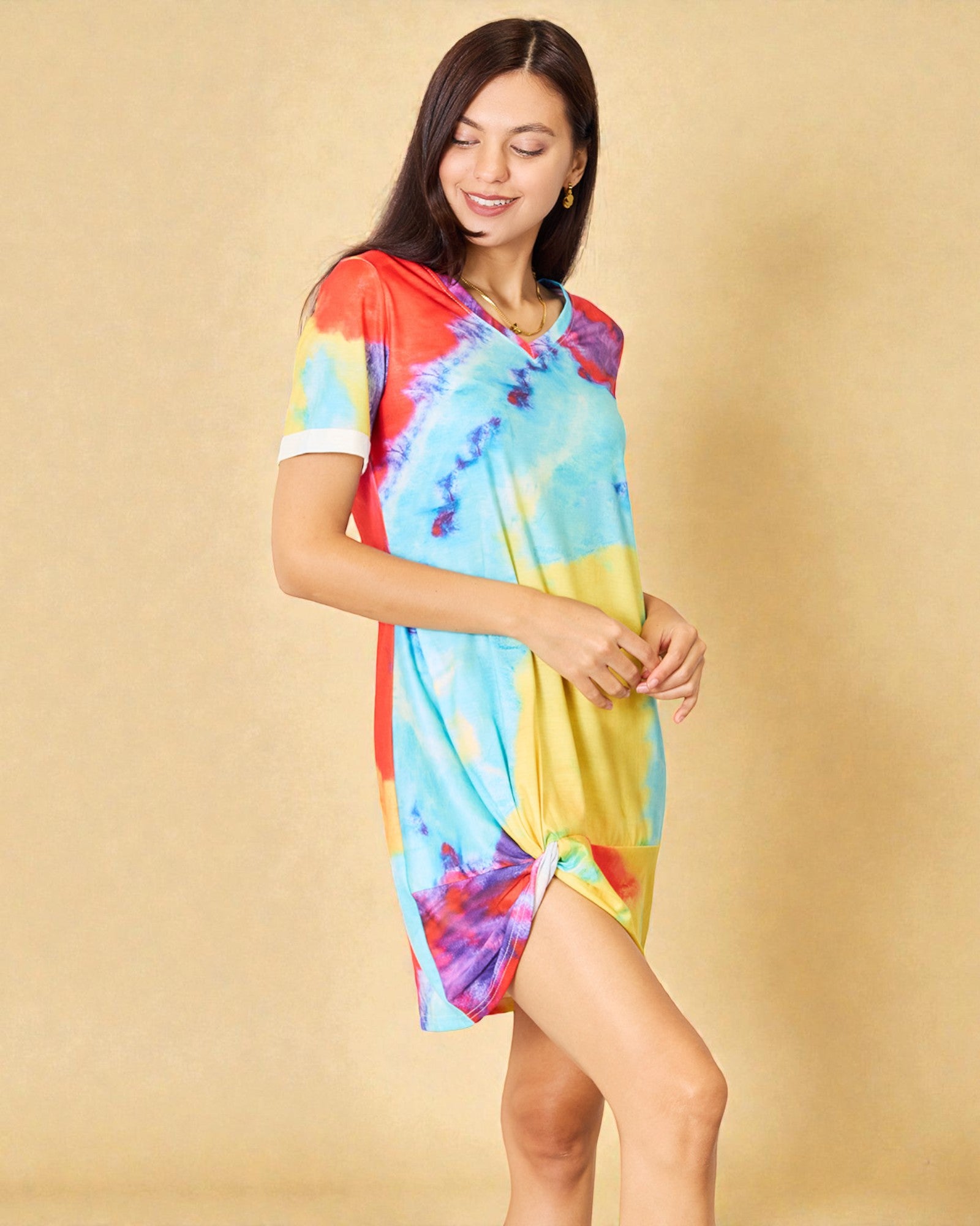 Woman wearing a colorful tie-dye dress against a beige background
