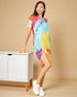 Woman wearing a colorful tie-dye dress standing next to a white cabinet on a beige background