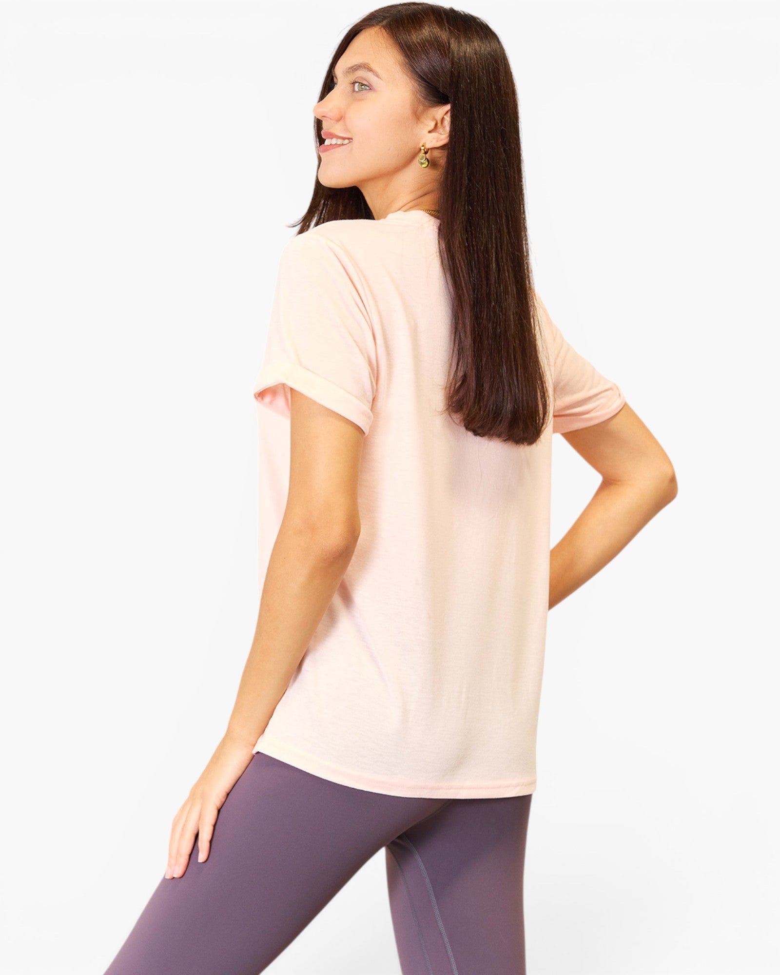 A woman shown from the back wearing a light pink short-sleeve t-shirt and purple leggings against a plain white background.