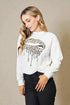 Woman wearing a white sweatshirt with a leopard print design on a beige background