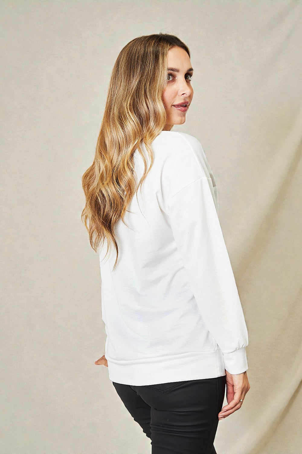 Woman wearing a white sweatshirt against a beige background