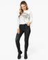 A woman modeling a white sweatshirt with a gold and black leopard print graphic, paired with black skinny jeans and black ankle boots, against a plain white background.