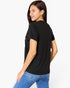 A woman wearing a black short-sleeve t-shirt and blue jeans, shown from a three-quarters back view against a plain white studio background.