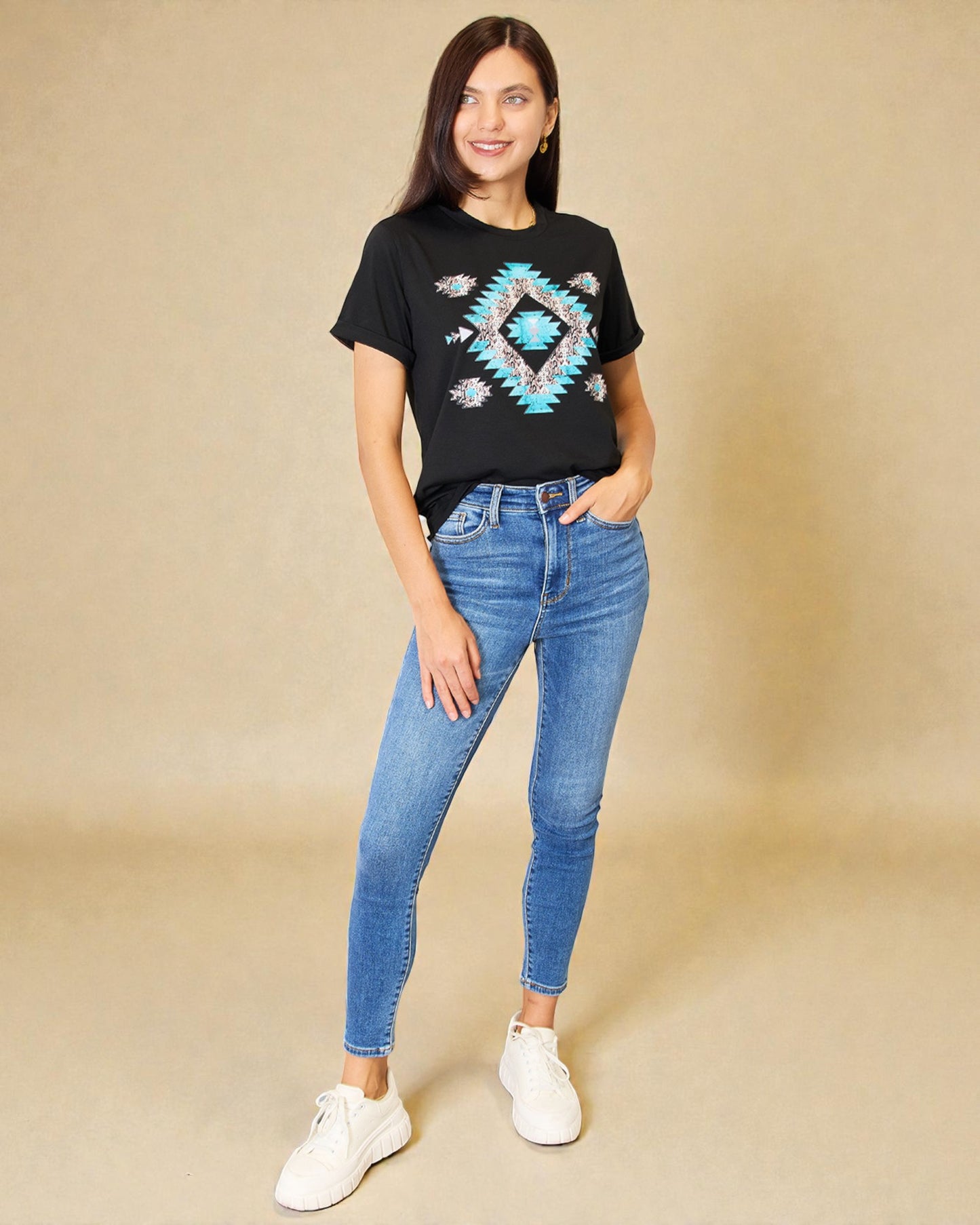 Woman wearing a black t-shirt with a geometric design and blue jeans on a beige background