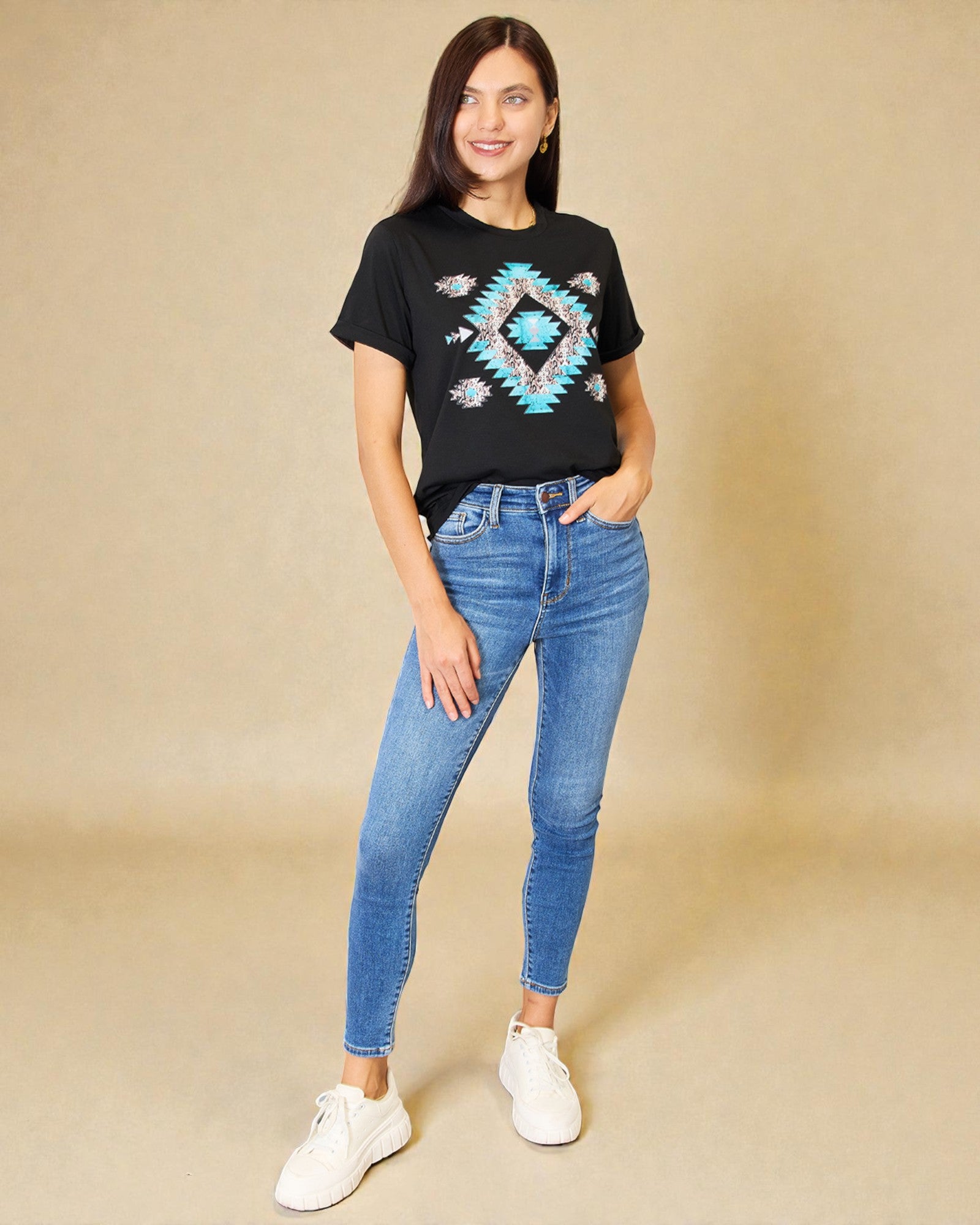Woman wearing a black t-shirt with a geometric design and blue jeans on a beige background