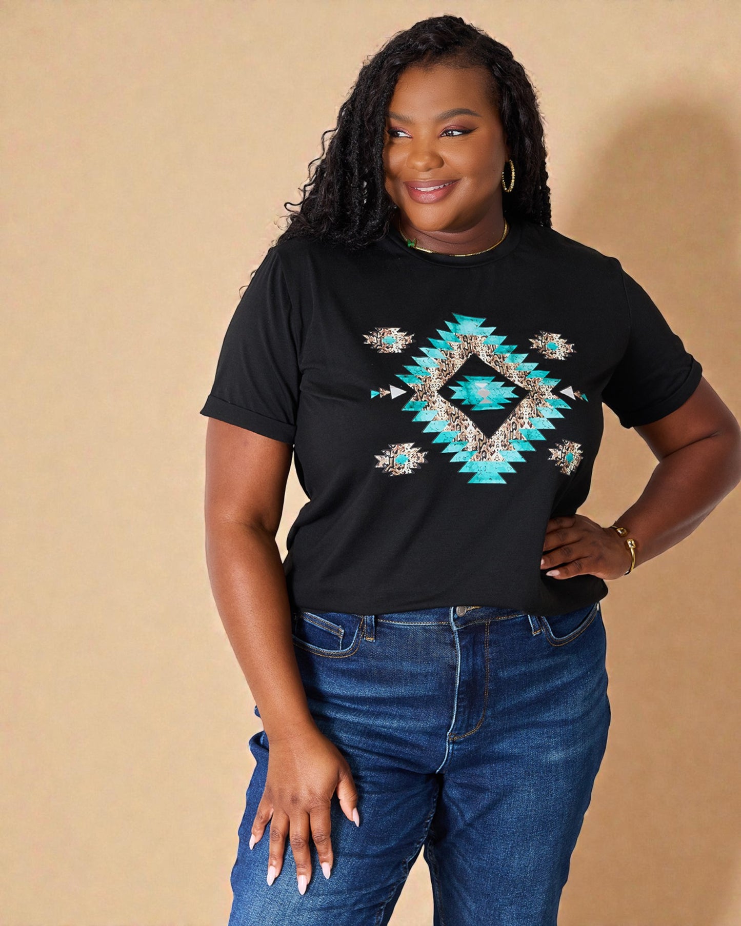 Woman wearing a black t-shirt with a blue geometric design and blue jeans against a beige background