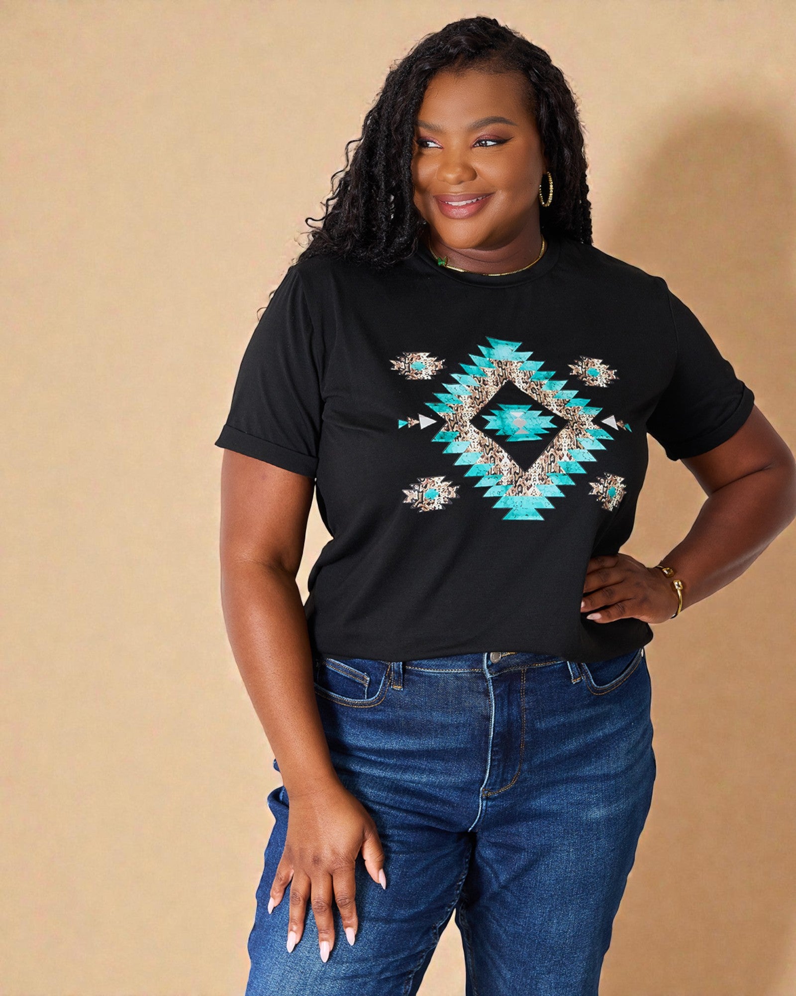 Woman wearing a black t-shirt with a blue geometric design and blue jeans against a beige background