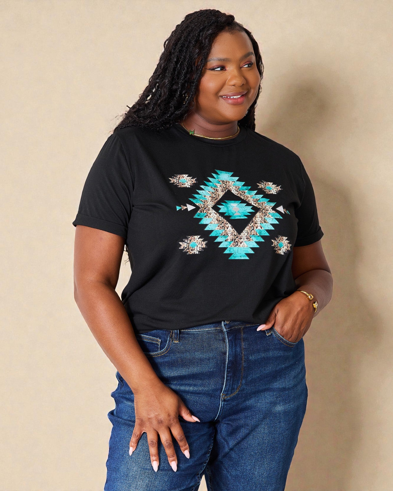 Woman wearing a black t-shirt with a blue geometric design and blue jeans against a beige background