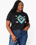A woman wearing a black short-sleeve t-shirt with a colorful geometric diamond pattern in turquoise, beige, and brown, paired with blue jeans, against a plain white background.