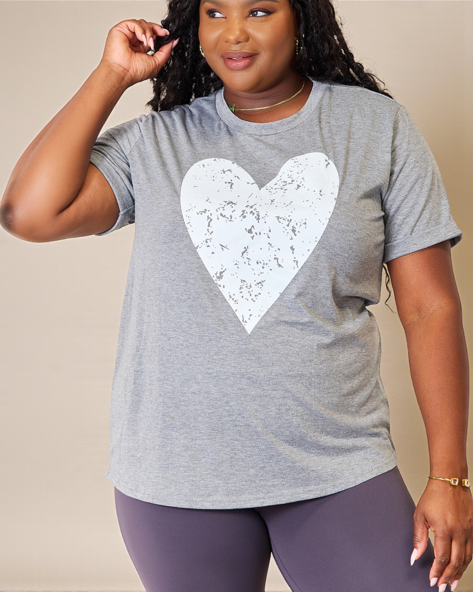 Person wearing a gray t-shirt with a white heart design on a beige background