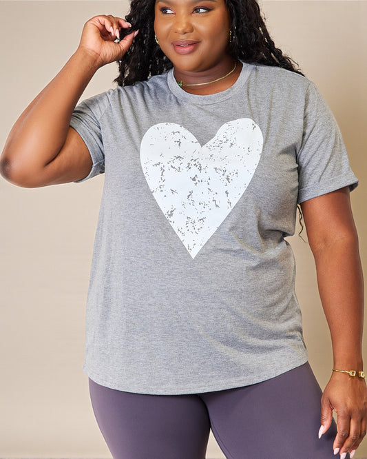 Person wearing a gray t-shirt with a white heart design on a beige background