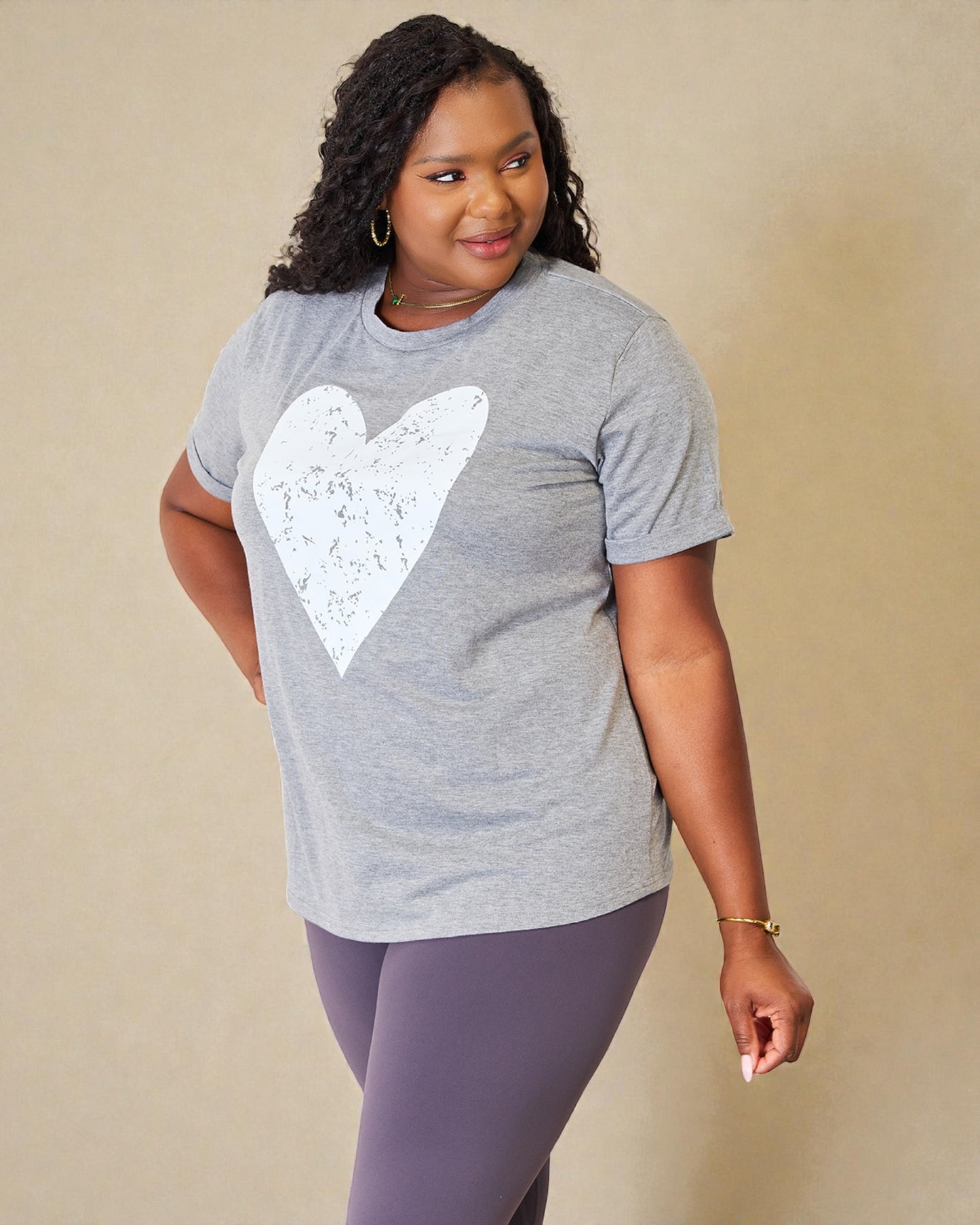 Woman wearing a gray t-shirt with a white heart design on a beige background