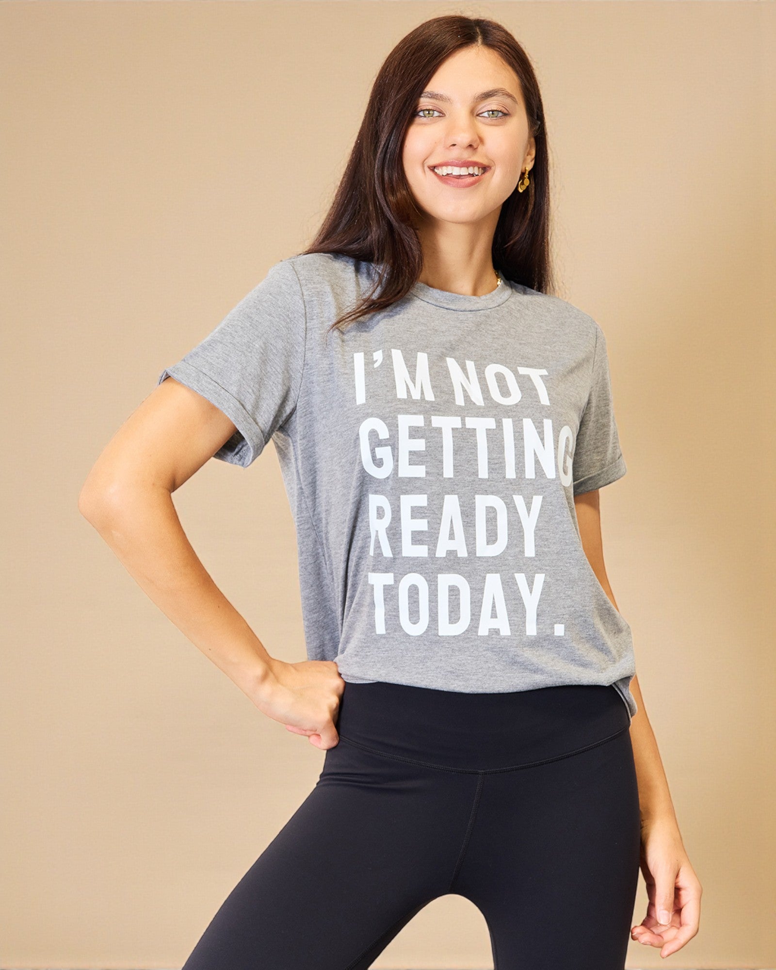 Woman wearing a gray t-shirt with 'I'm not getting ready today' text on a beige background