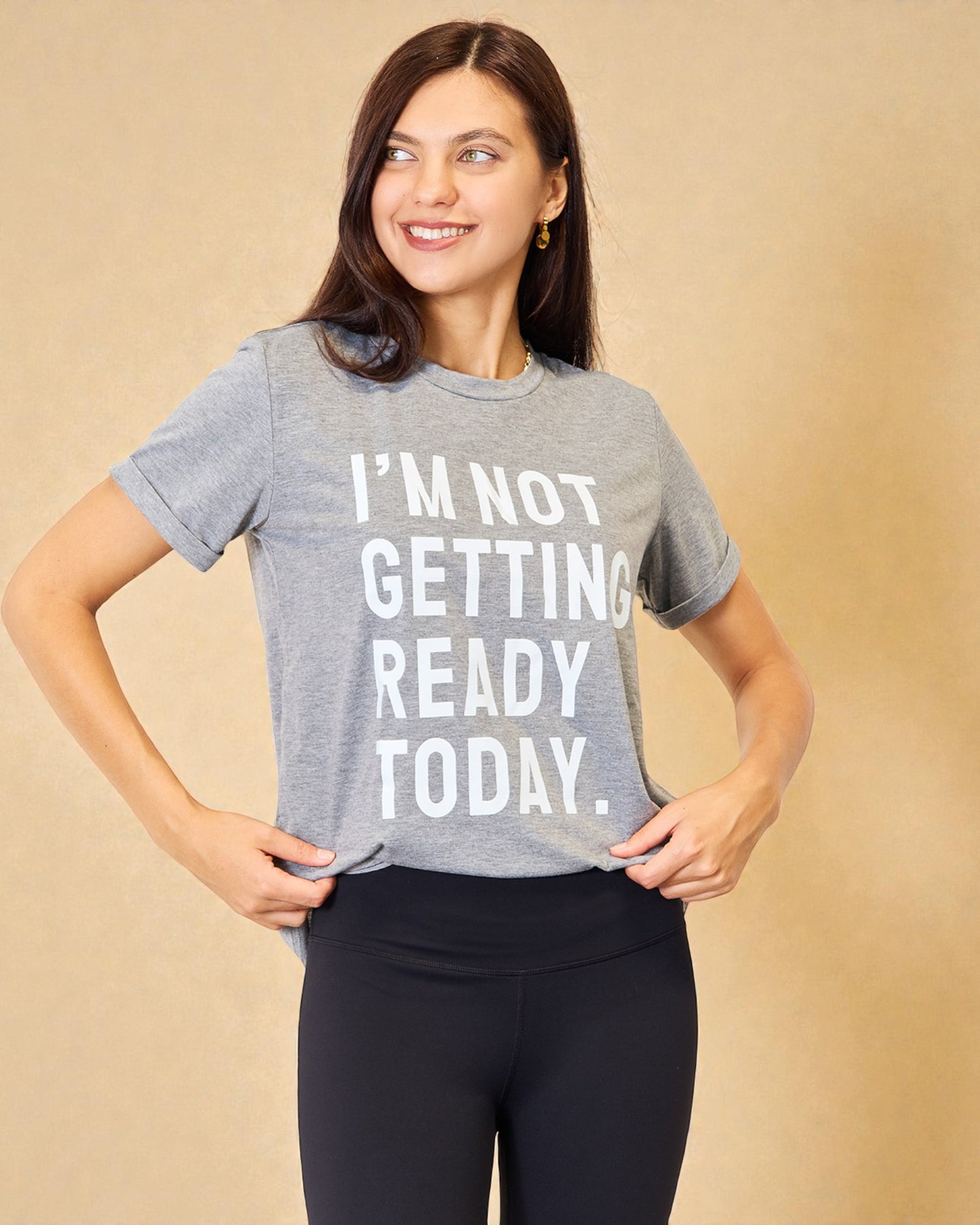 Woman wearing a gray t-shirt with 'I'm not getting ready today' text on a beige background