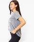 A woman wearing a heather gray short-sleeve graphic t-shirt and black leggings, shown from a side profile against a plain white studio background.