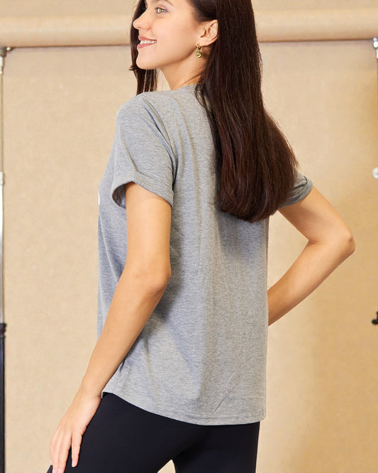 Woman wearing a gray t-shirt and black pants against a beige background