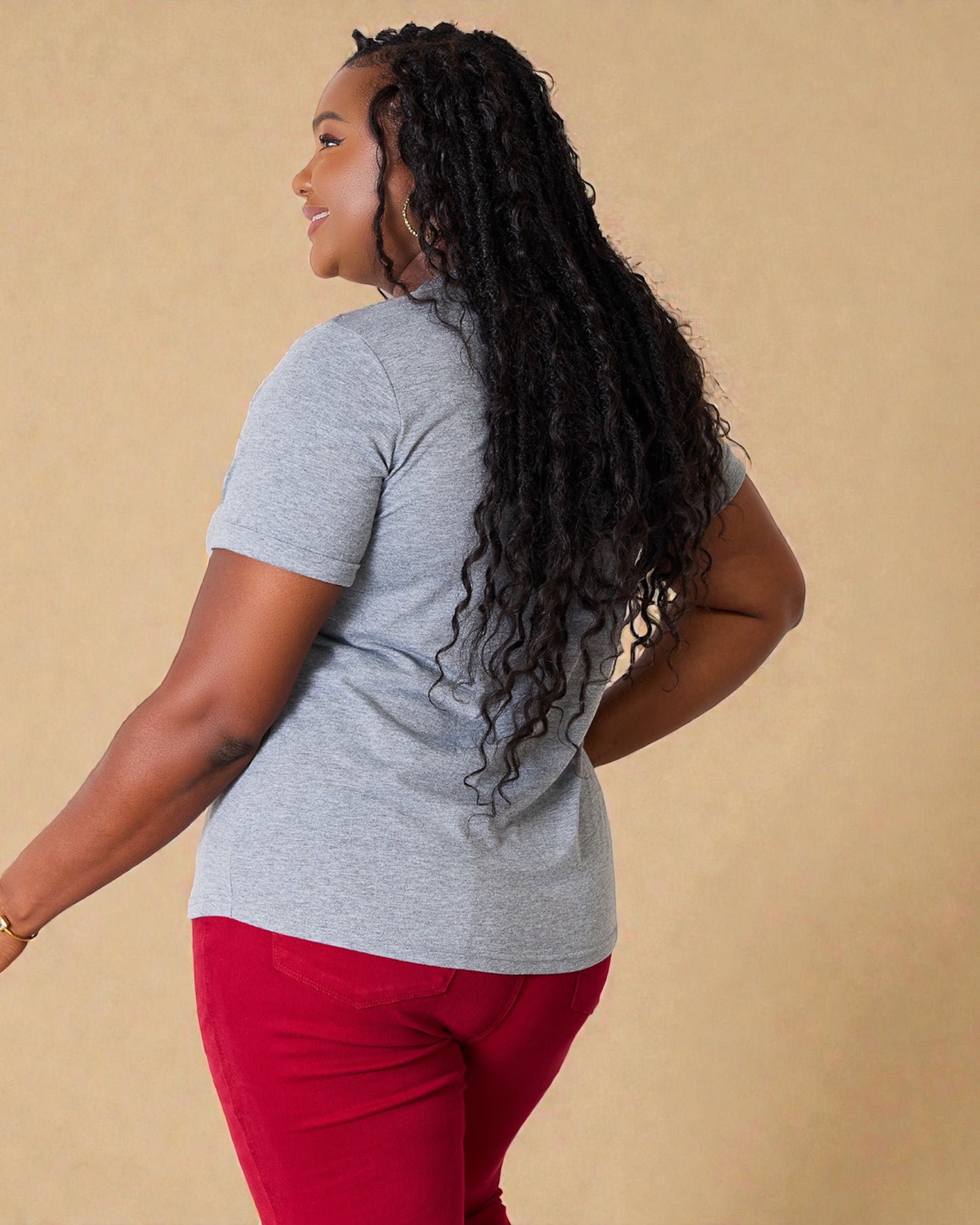 Woman wearing a gray shirt and red pants against a beige background