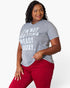 A woman wearing a heather gray graphic t-shirt with the text 'I'M NOT GETTING READY TODAY.' in white, paired with red pants, against a plain white background.