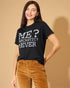 Woman wearing a black t-shirt with text, standing against a beige background