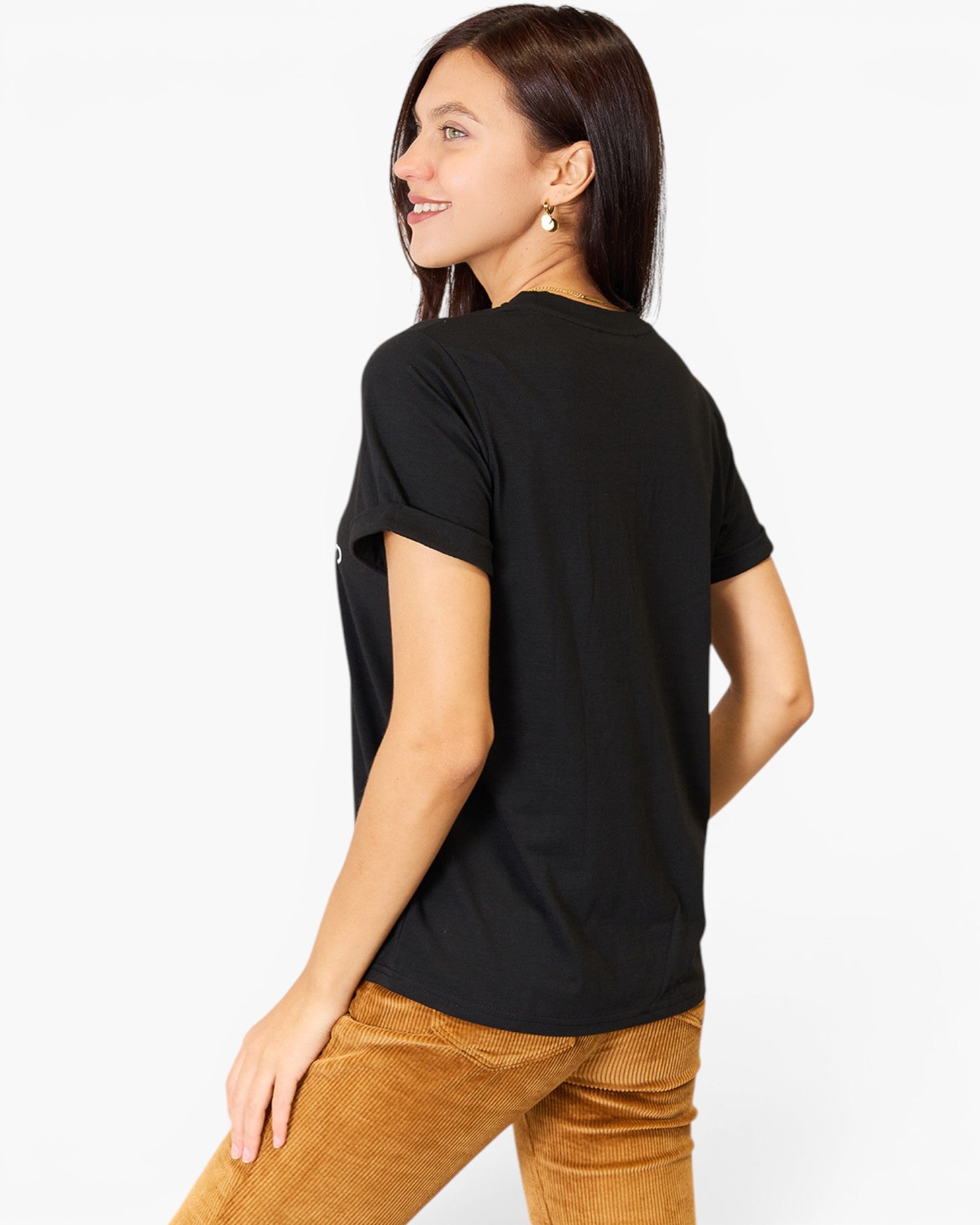 A woman wearing a black short-sleeve crewneck t-shirt and brown corduroy pants, shown from a three-quarters back view against a plain white background.