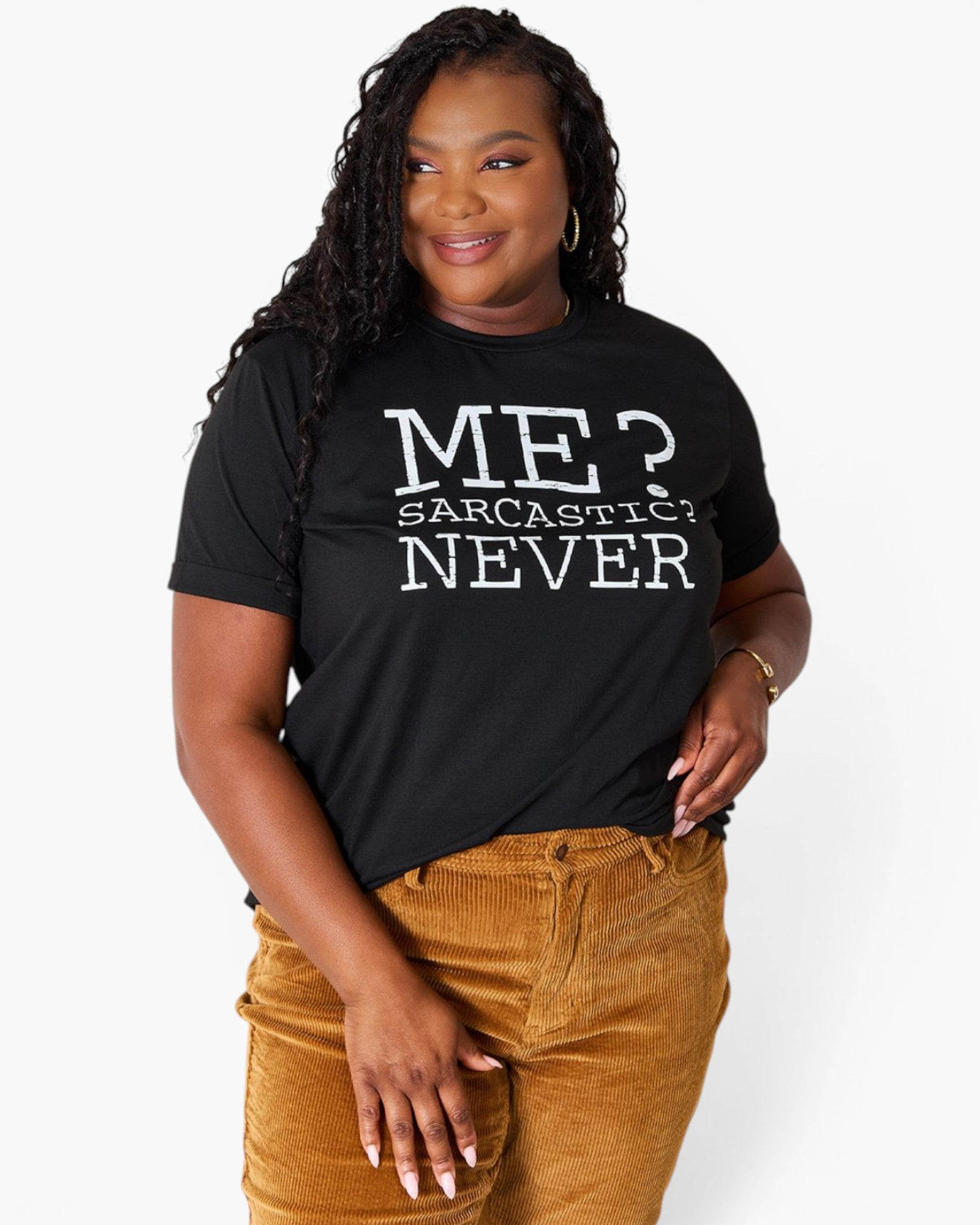 A woman wearing a black graphic t-shirt with the text 'ME? SARCASTIC? NEVER' in white, paired with brown corduroy pants, against a light gray background.