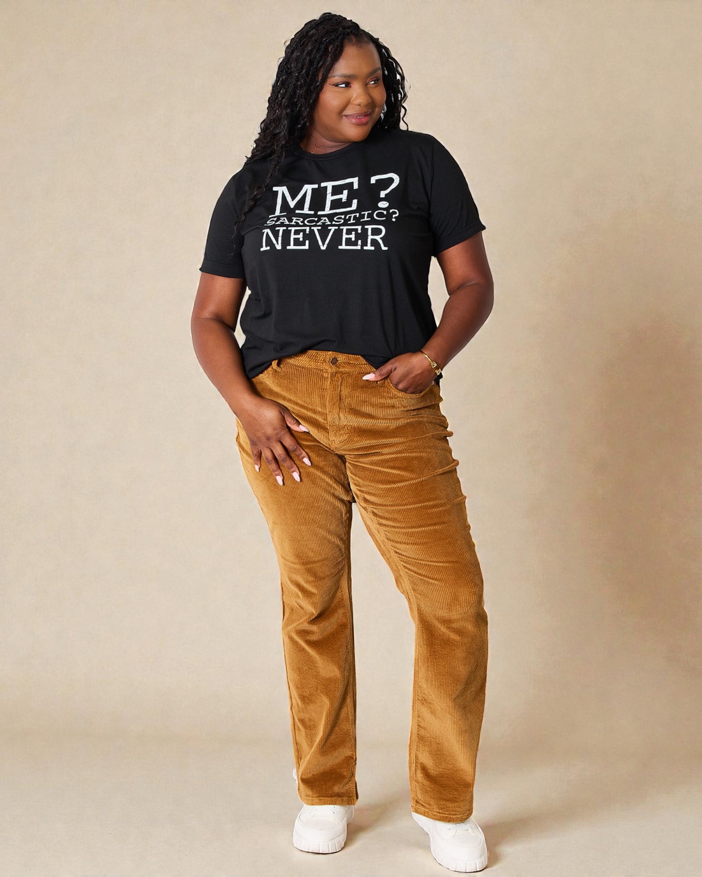 Person wearing a black t-shirt with text and brown pants on a beige background
