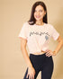 Woman wearing a pink 'mama' t-shirt with black text and a heart design on a beige background