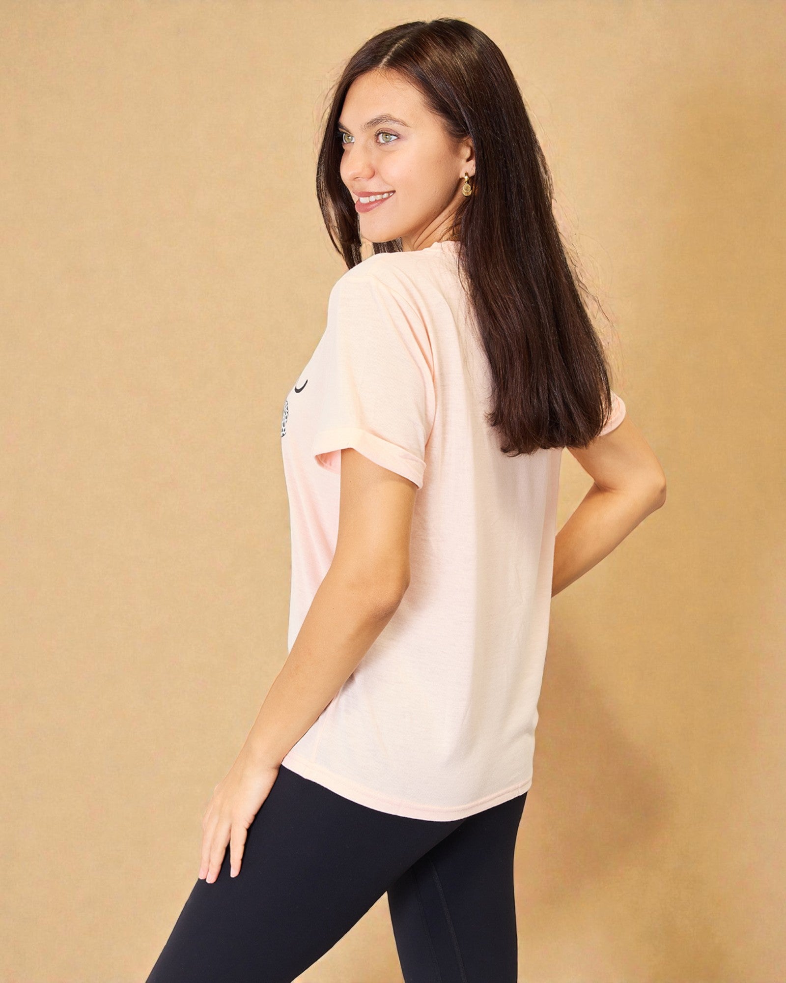 Woman wearing a light pink t-shirt with a Nike logo on a beige background