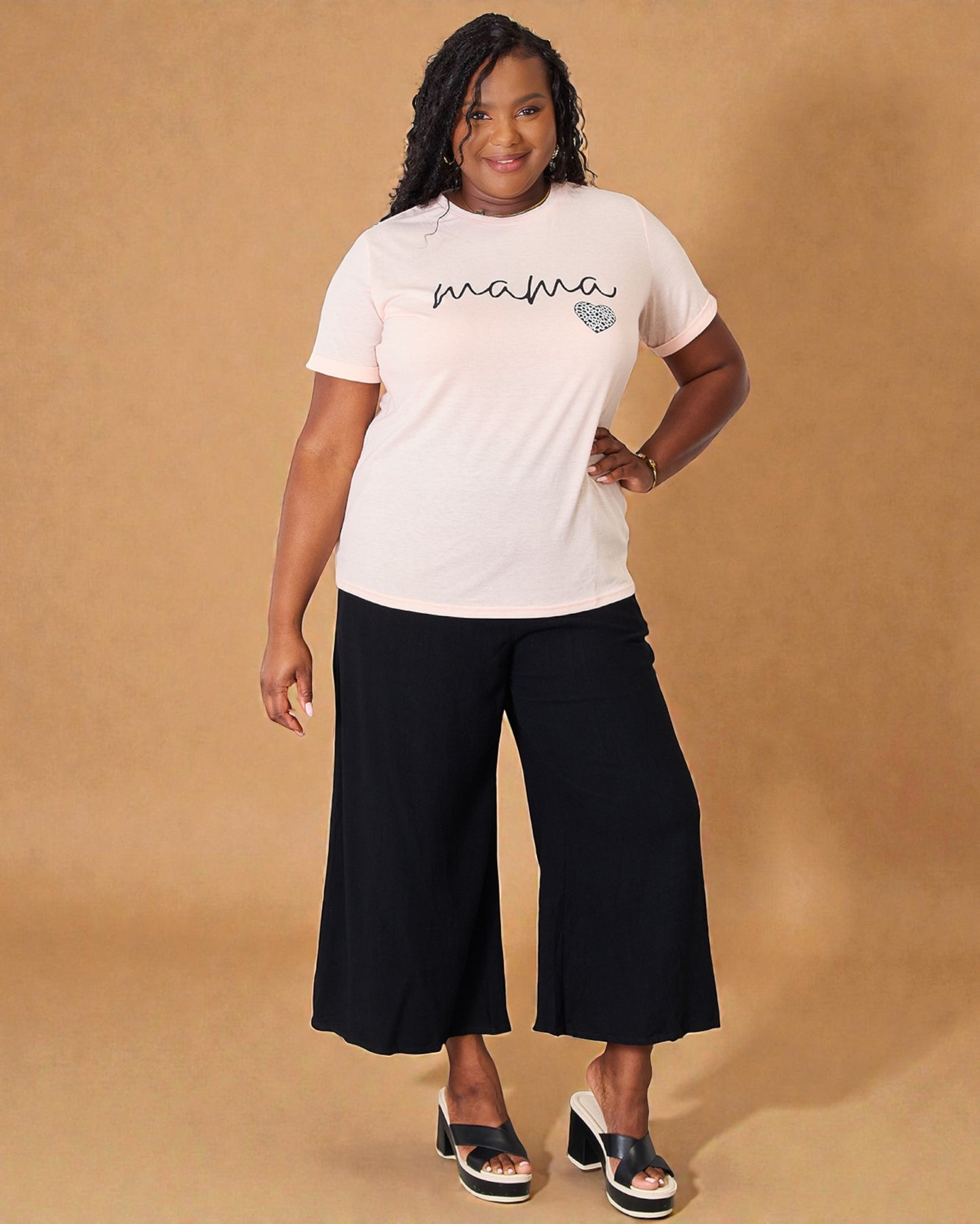 Woman wearing a white t-shirt with 'mama' printed on it against a beige background